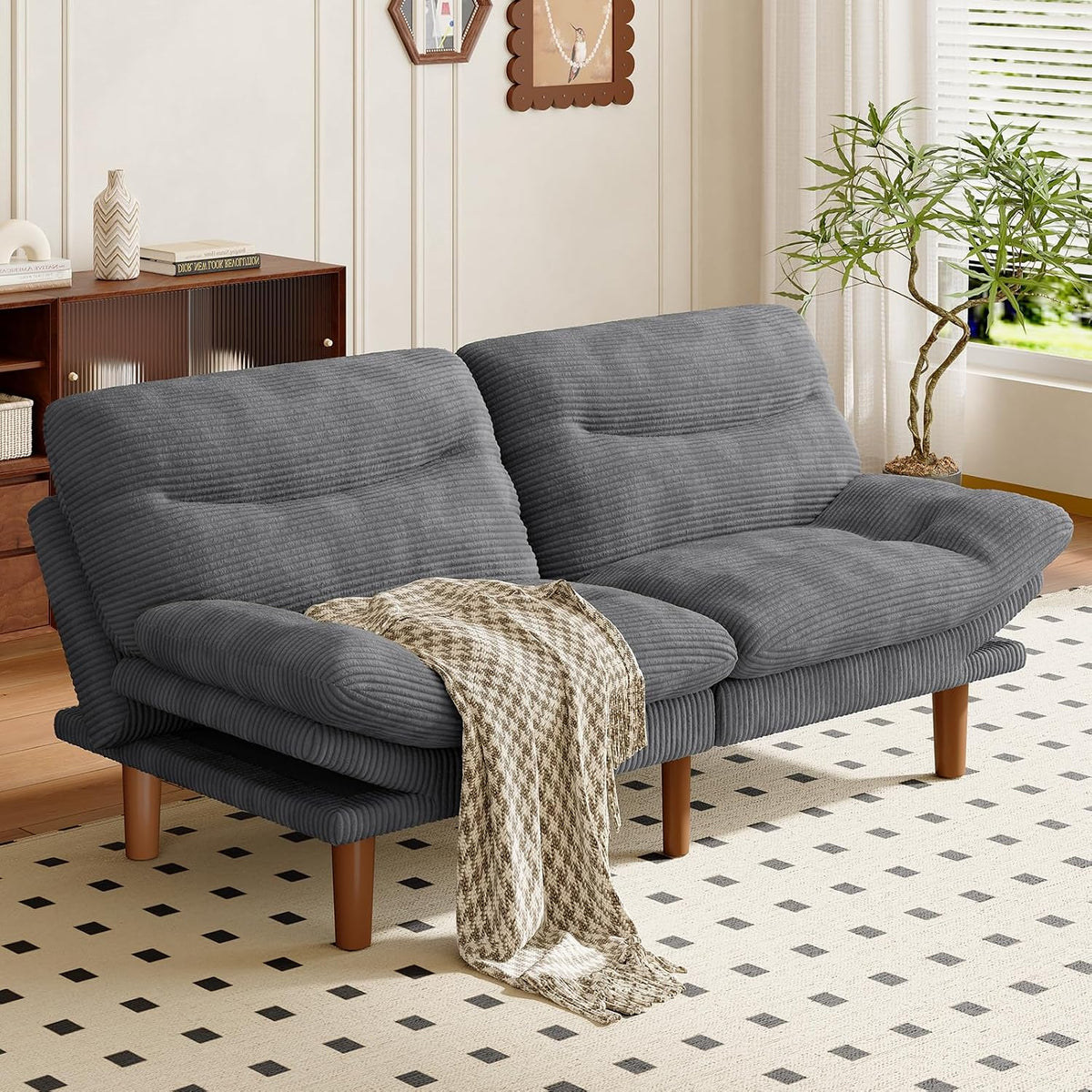 Gray corduroy futon sofa set in a living room with a draped throw over the seat