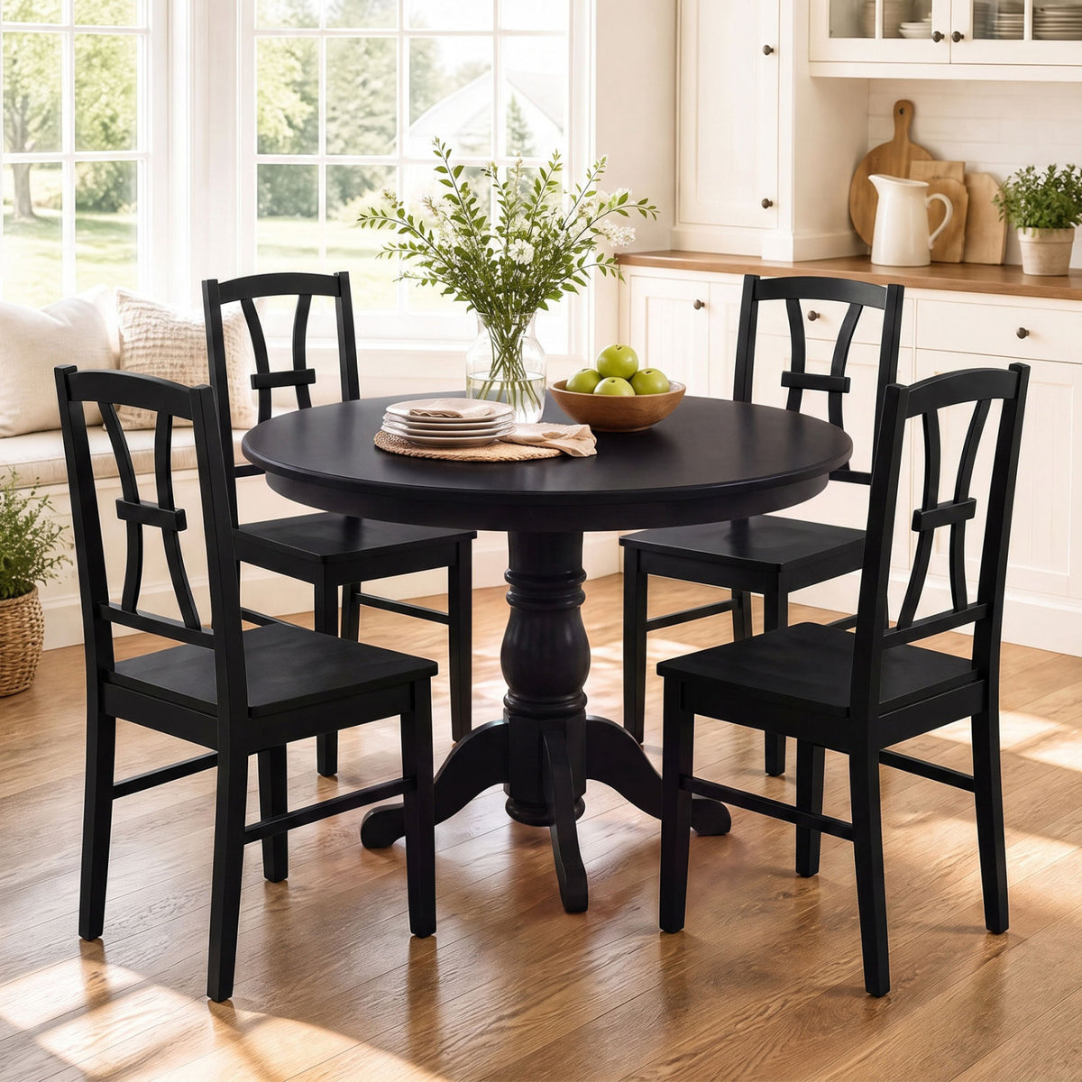 Four black cross-back chairs surround a round black pedestal table in a bright dining nook.