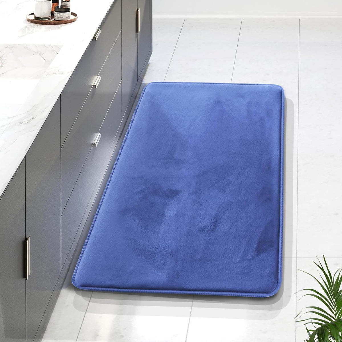 Top-down view of a blue plush rectangular runner placed along a gray vanity on white tile floor.
