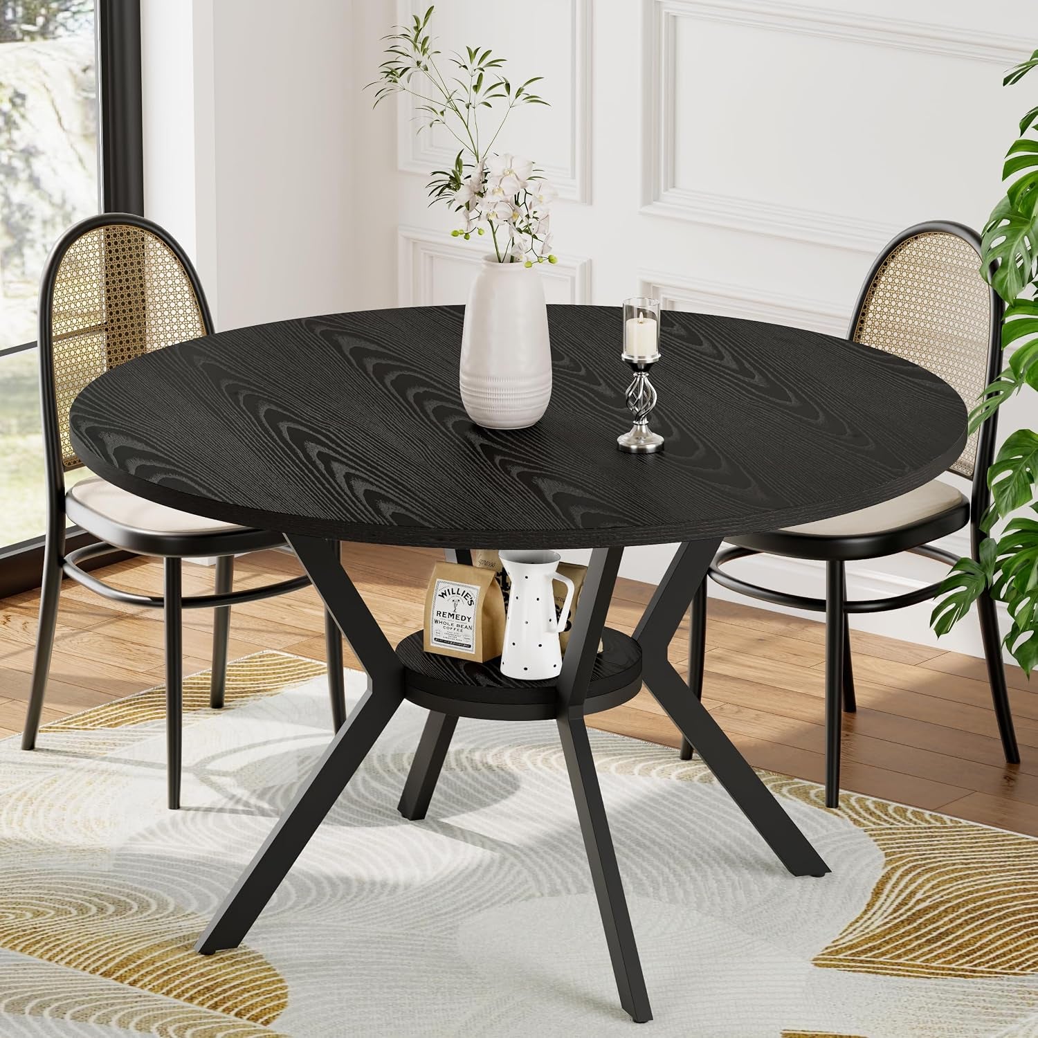 Round dining table with black wood-grain top and black metal angled legs with small center shelf.