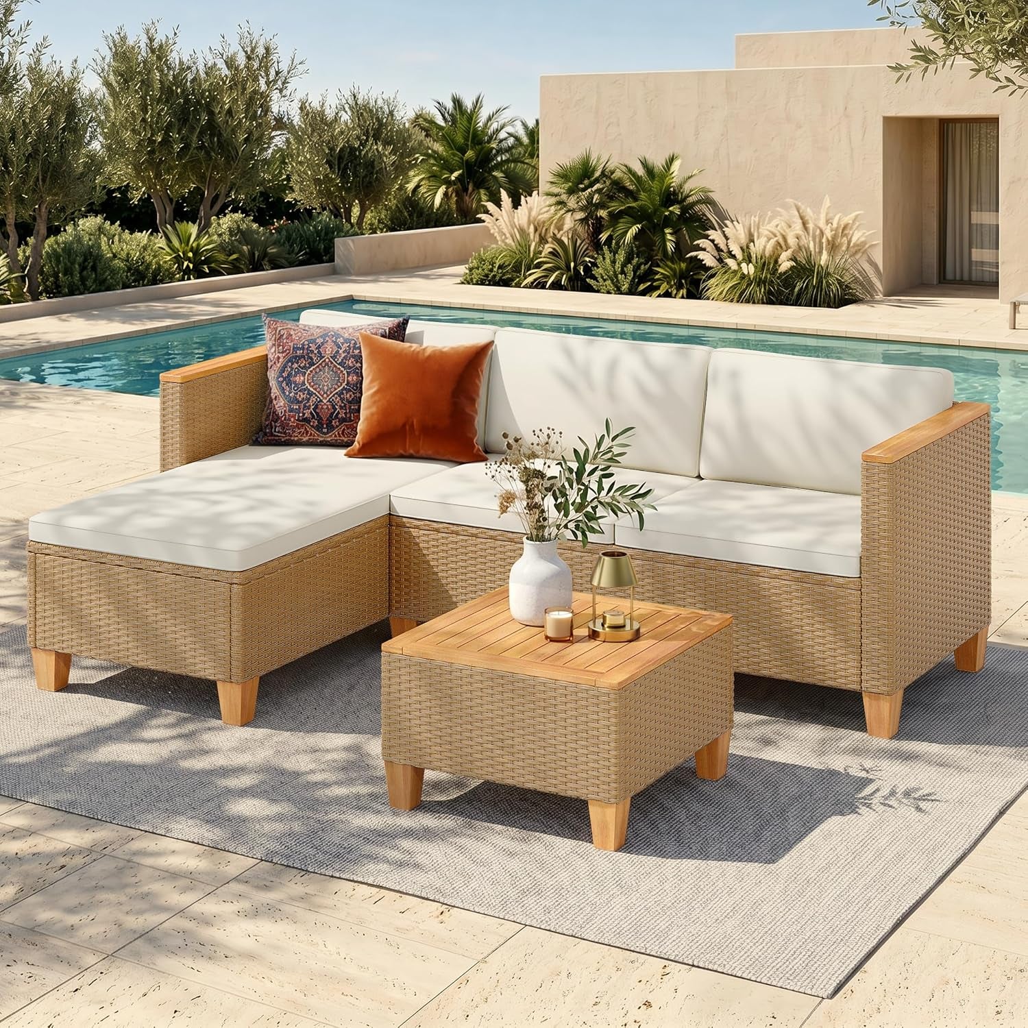 Beige handwoven wicker sectional with white cushions and wood-top coffee table at poolside, angled front view