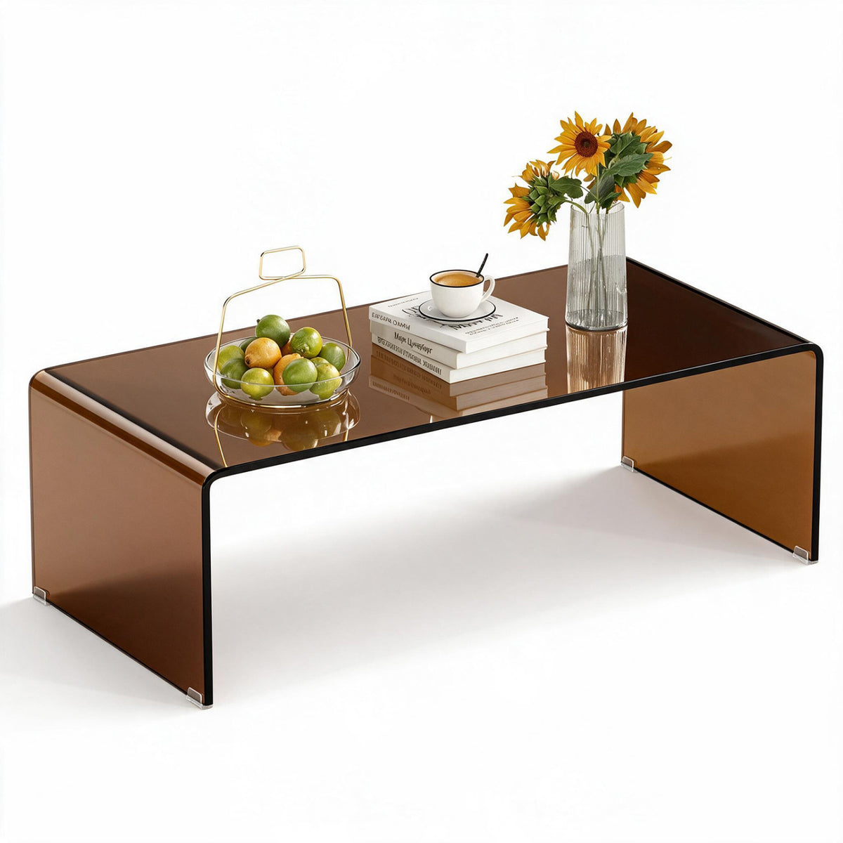 Dark glass coffee table arranged with a fruit bowl, stacked books, a cup, and a vase of sunflowers.