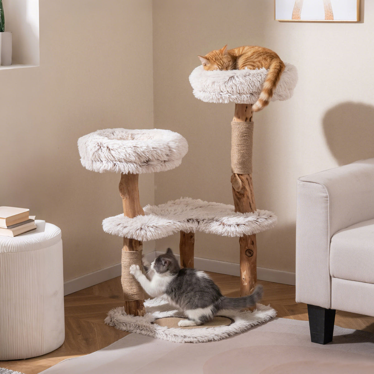 Two cats use a branch-style cat tree, with one curled on the top perch and another reaching up to scratch.