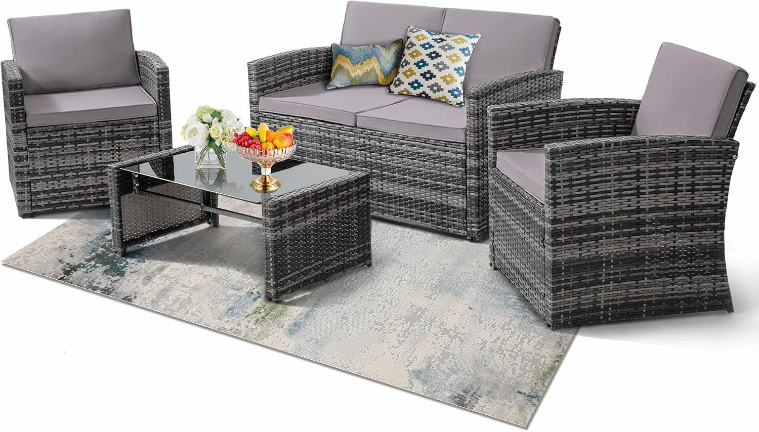 Three-piece wicker seating and glass-top coffee table on a rug with gray cushions and decorative pillows.