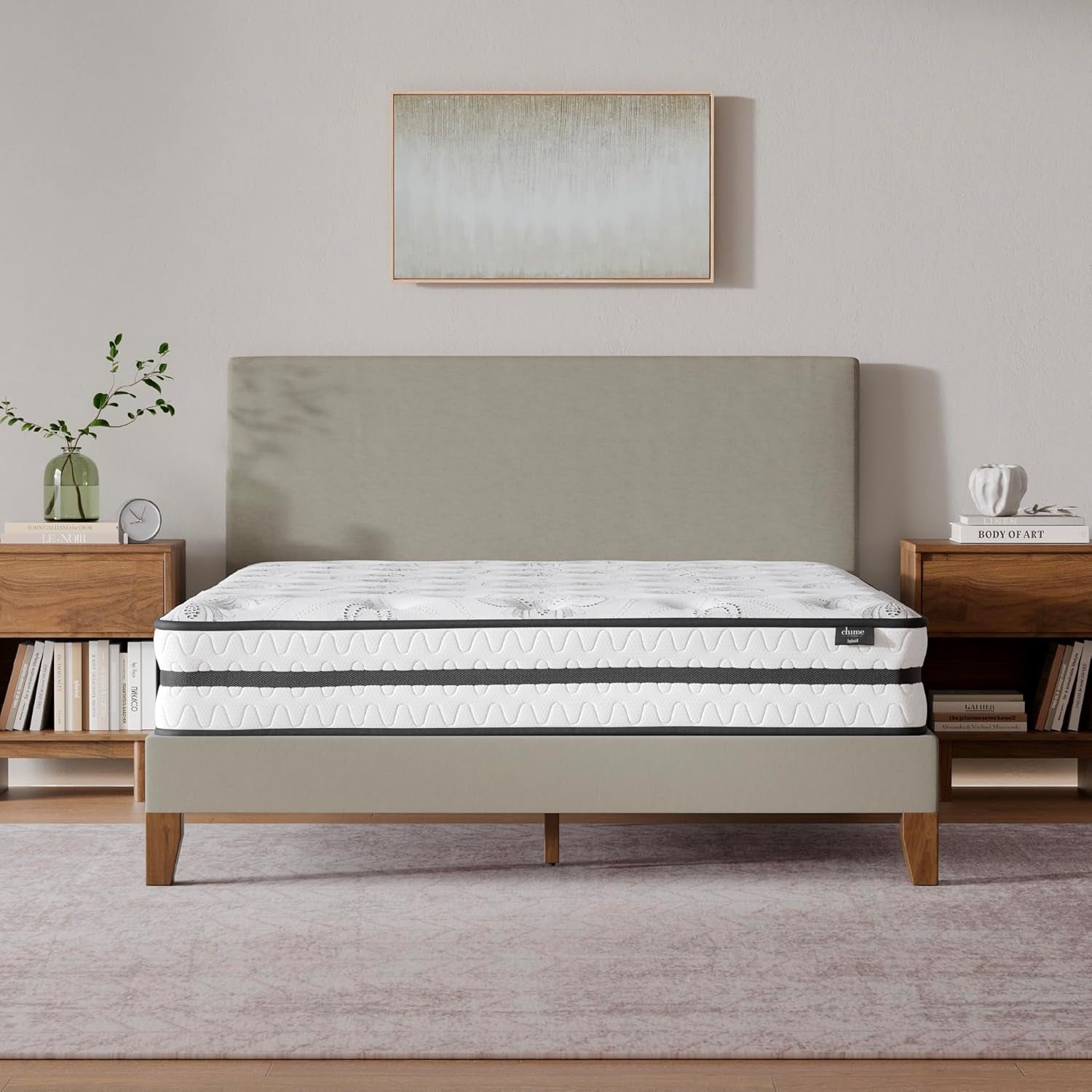 Centered bedroom shot of the mattress on a low platform bed with pillows and bedside tables visible.
