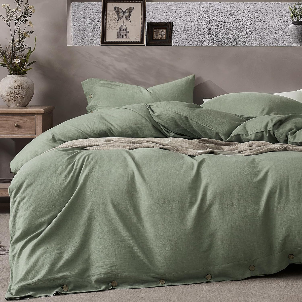 Bed styled with sage green duvet and pillows, wooden buttons along the duvet hem visible.