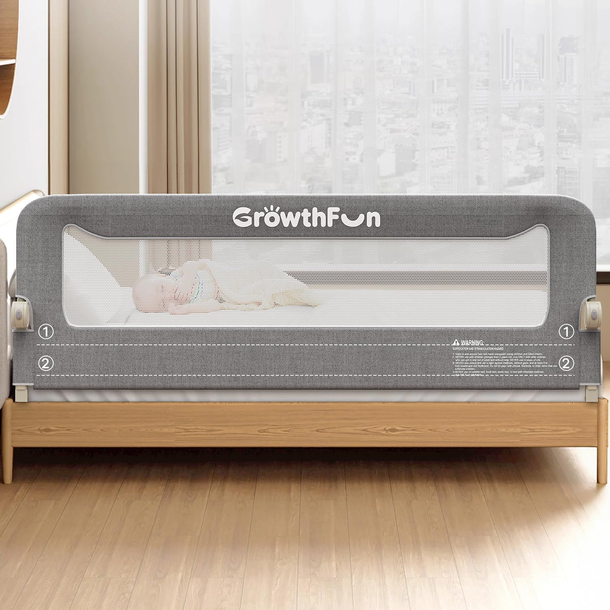 Gray mesh bed rail installed on a wooden bed frame with a sleeping baby visible behind the panel.