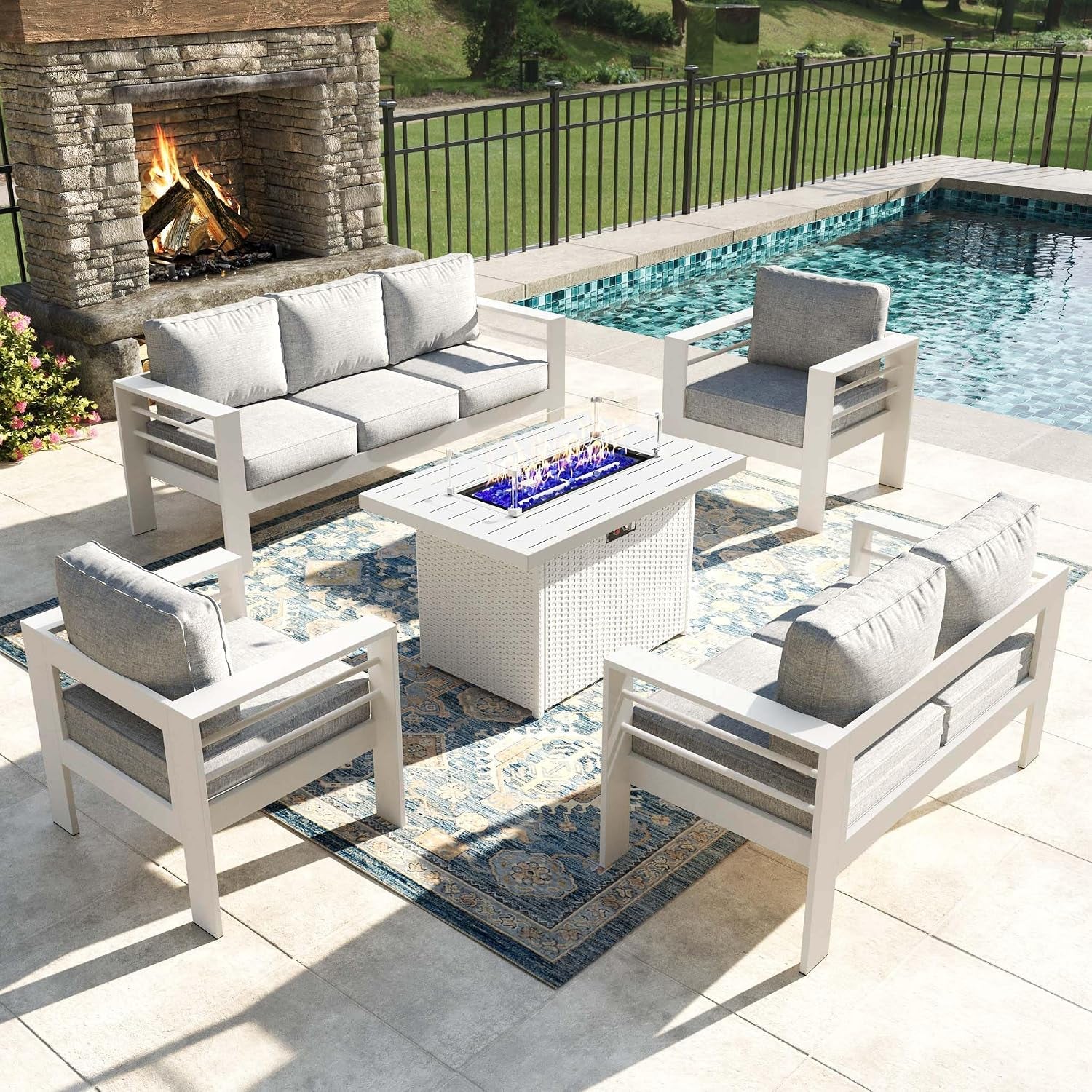 Same patio conversation set in a white-framed finish with gray cushions and a light-colored fire table on a patterned rug