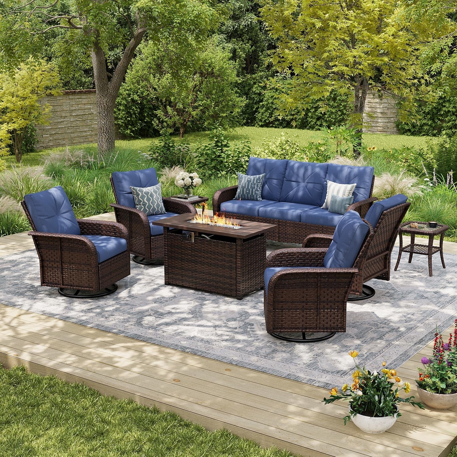 Wide view of the wicker seating arrangement with blue cushions and a lit fire pit at center on a patterned rug