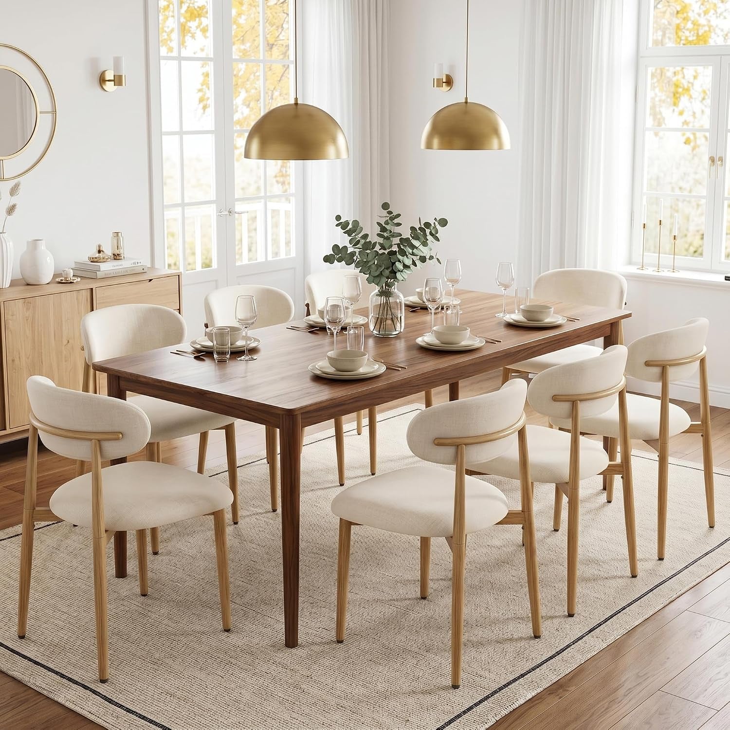 Rectangular wood table surrounded by eight beige-upholstered chairs with light wood-grain metal legs in a bright dining