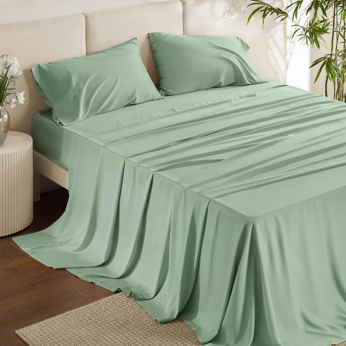 Soft green sheets and pillowcases shown on a bed with fabric cascading to the floor.