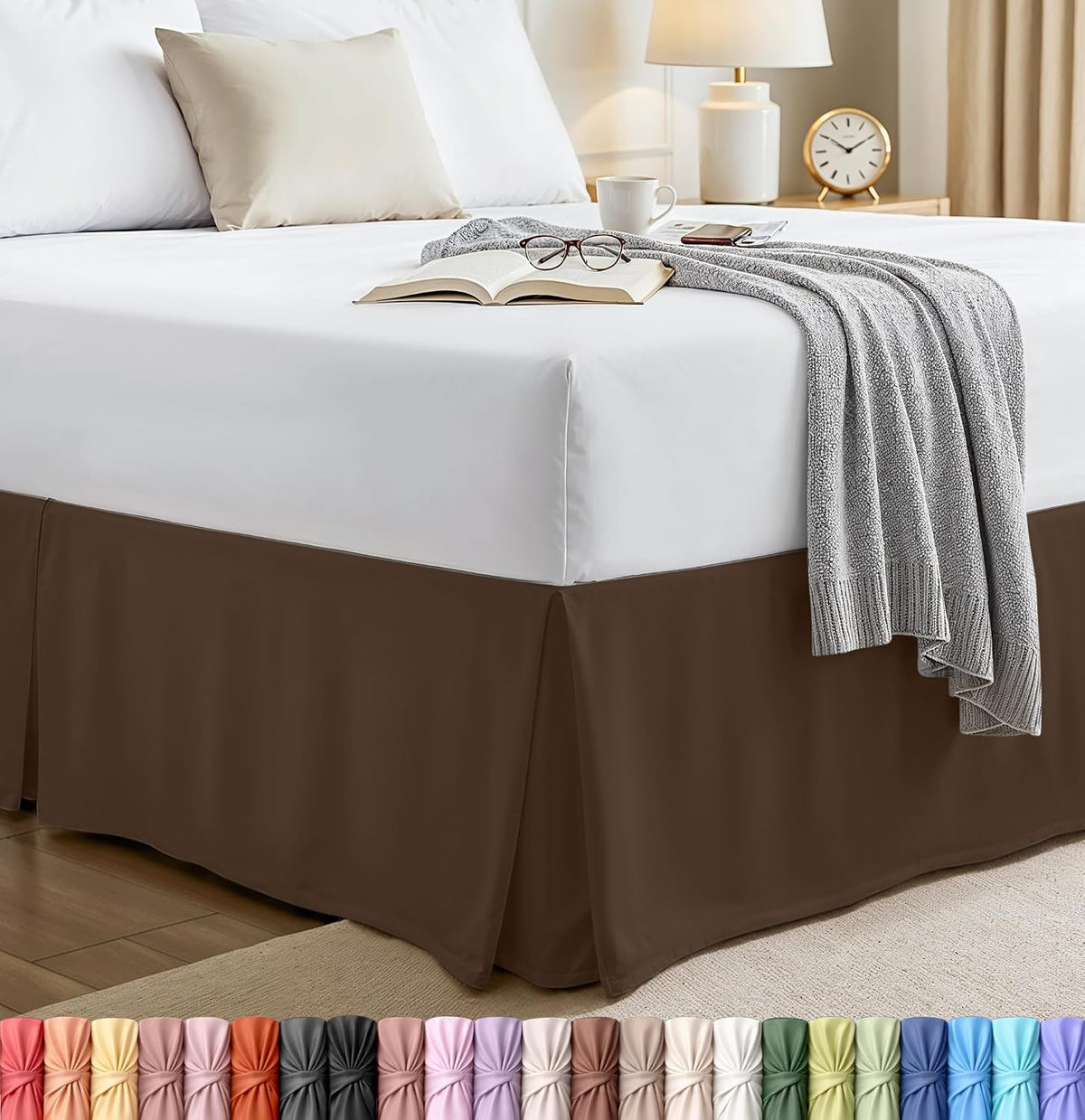 Corner view of a made bed with a white mattress and a brown pleated bed skirt draping to the floor.