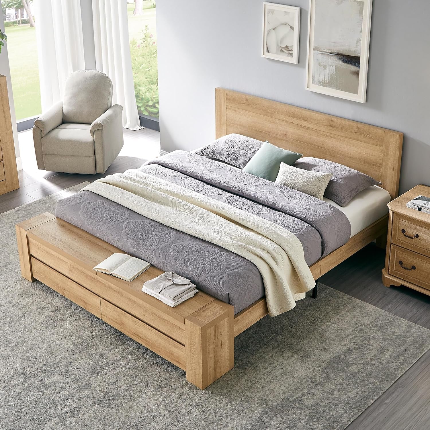 Angled overhead view of a light oak platform bed showing headboard, low storage bench and bedding.