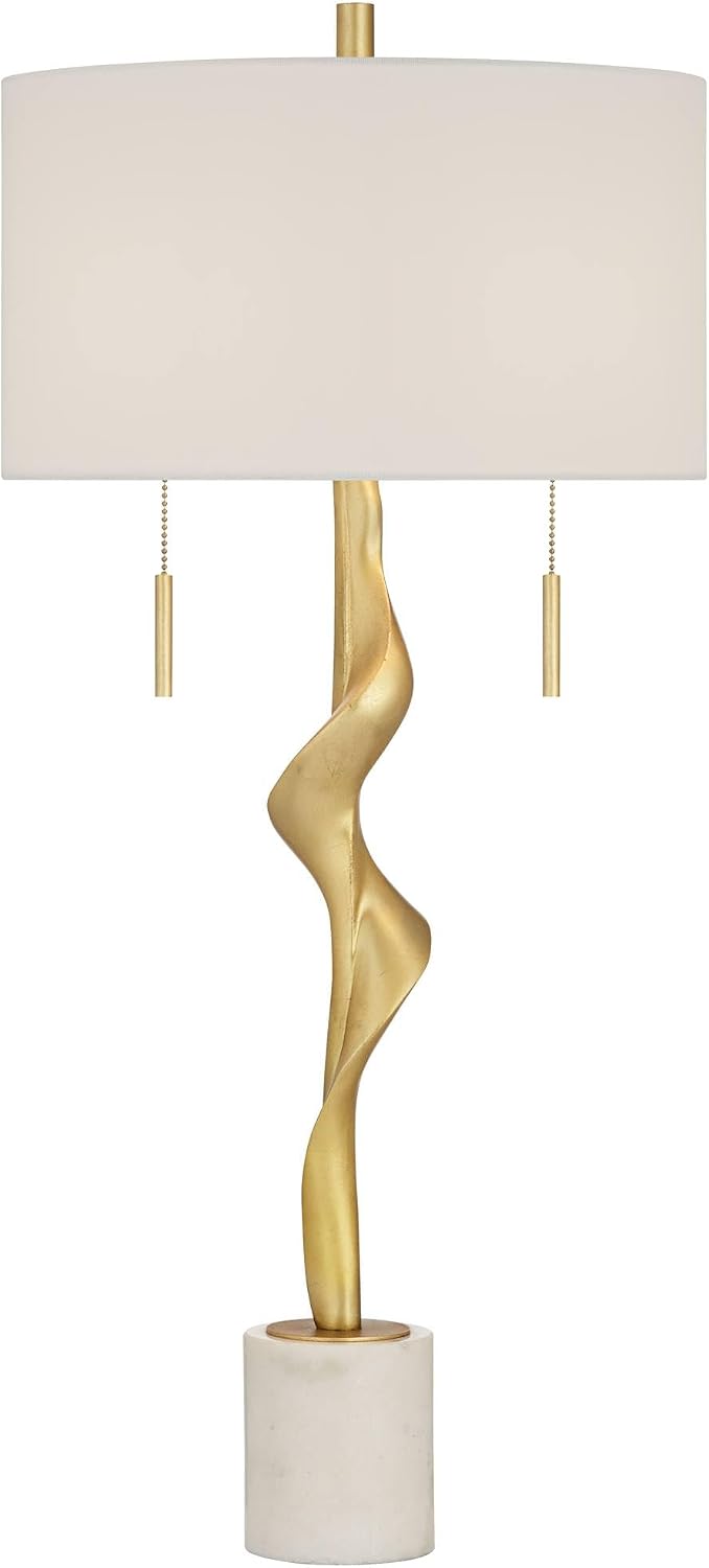 Front view of gold sculptural table lamp with off-white drum shade and white marble cylindrical base on a white background