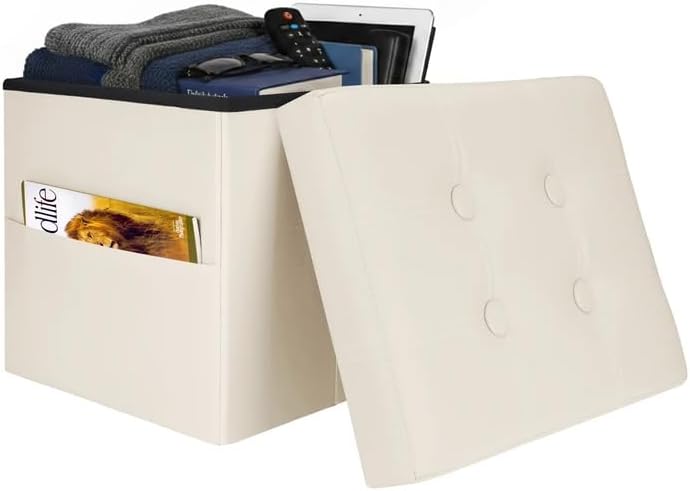 Cream faux-leather folding storage ottoman with lid removed, showing folded clothes, tablet, remote and a side pocket