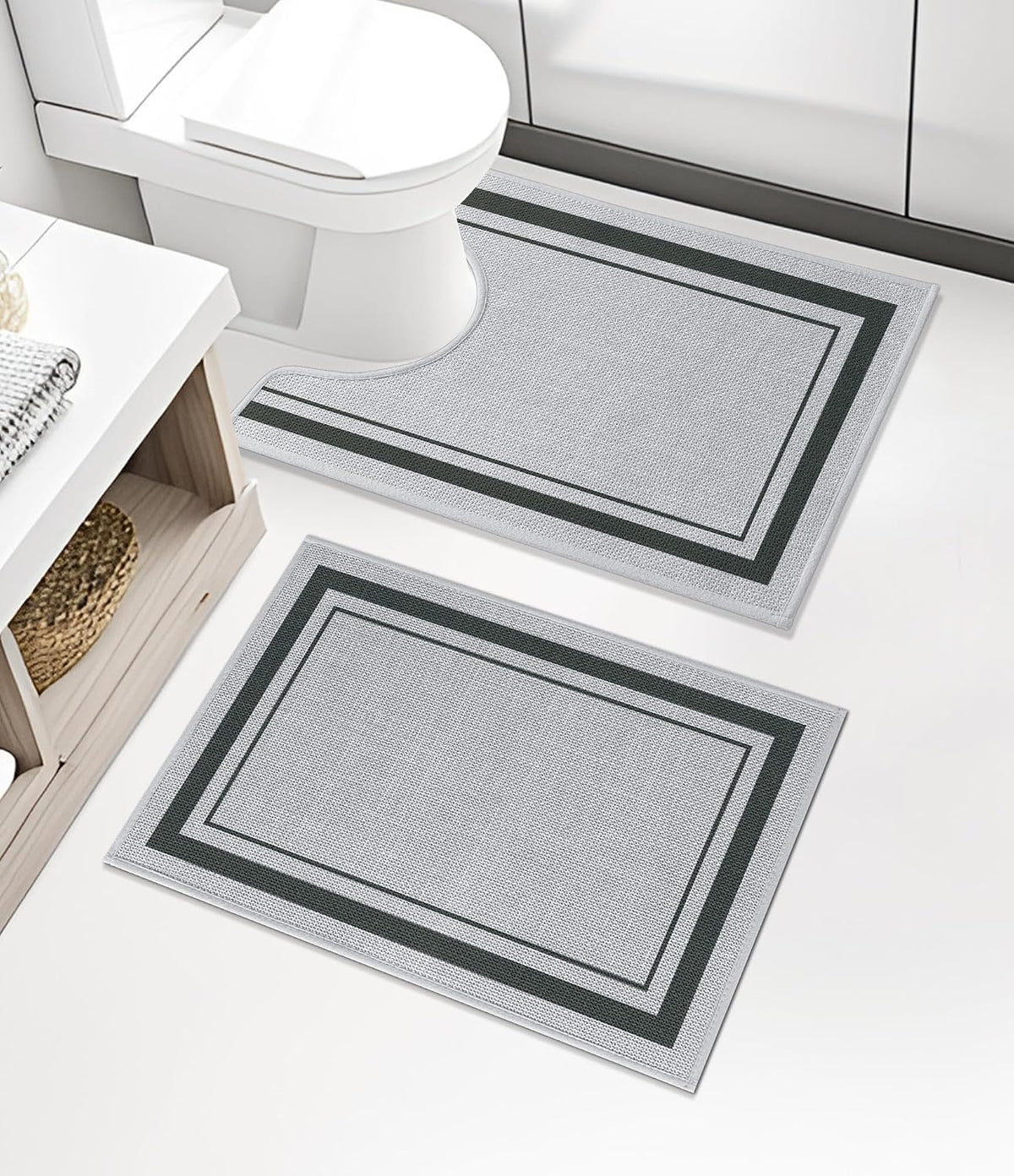 Two light gray bath rugs, one U-shaped around toilet and one rectangular, on a white bathroom floor