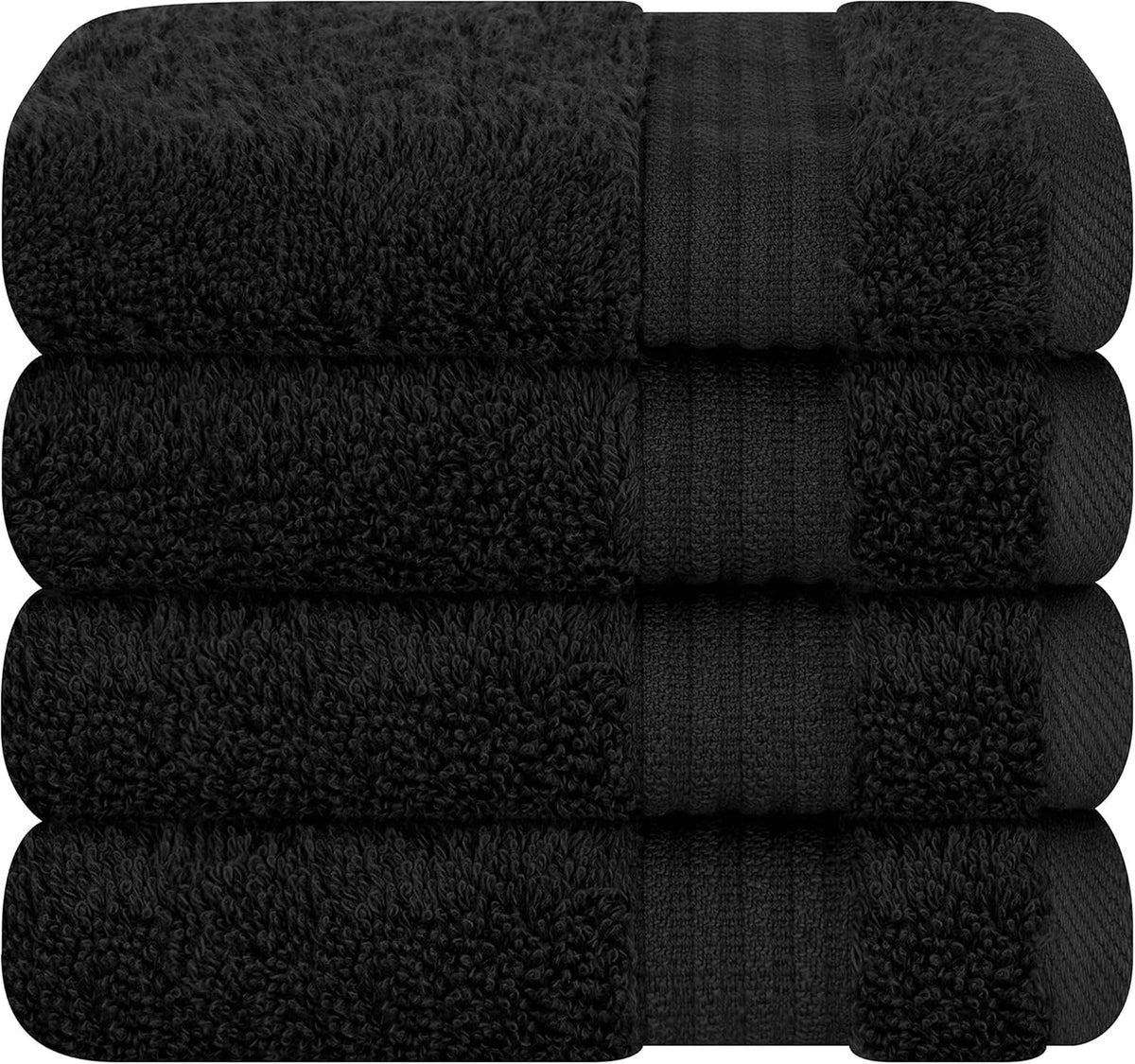 Side profile of four thick black towels stacked tightly to show plush loops and folded edges