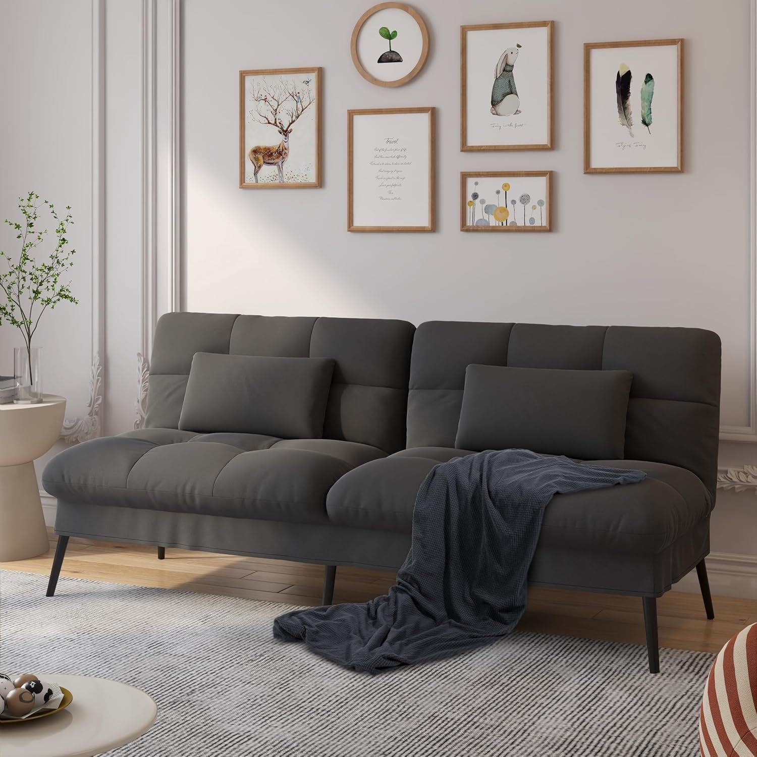 Dark gray futon sofa with matching pillows and a dark throw on a light rug in a living room.