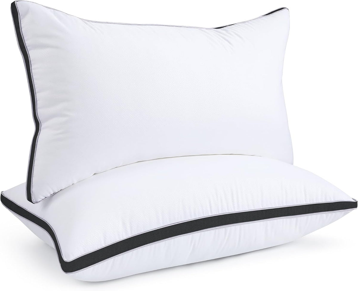 Two stacked white pillows with a dark charcoal piped edge and contrast band.