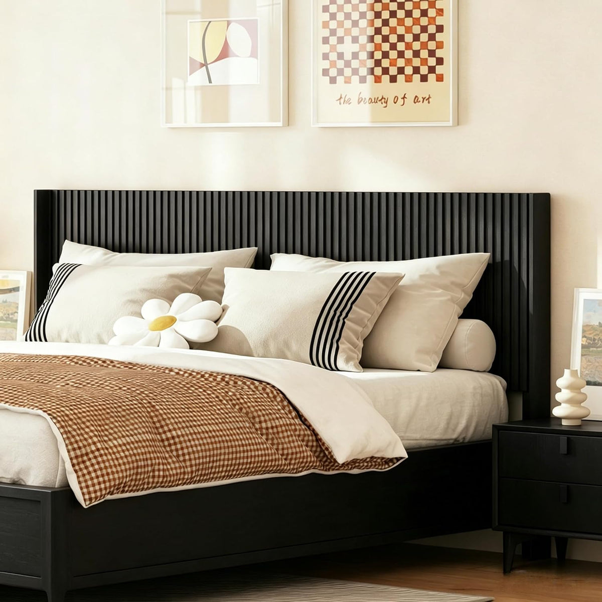 Straight-on bedroom image of a black vertical-fluted wall headboard framed by artwork above the bed.