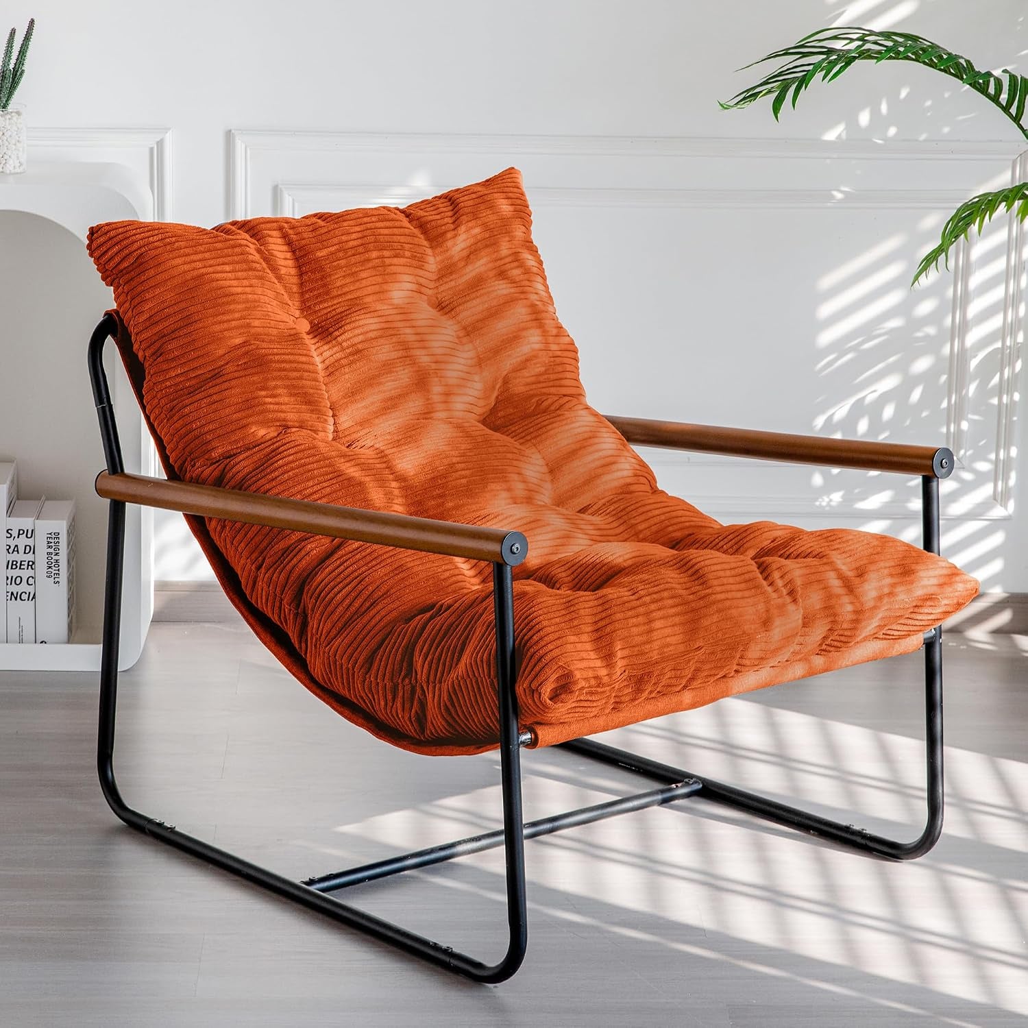 Same low lounge chair styled with a bright orange corded cushion, black metal frame and wooden armrests.
