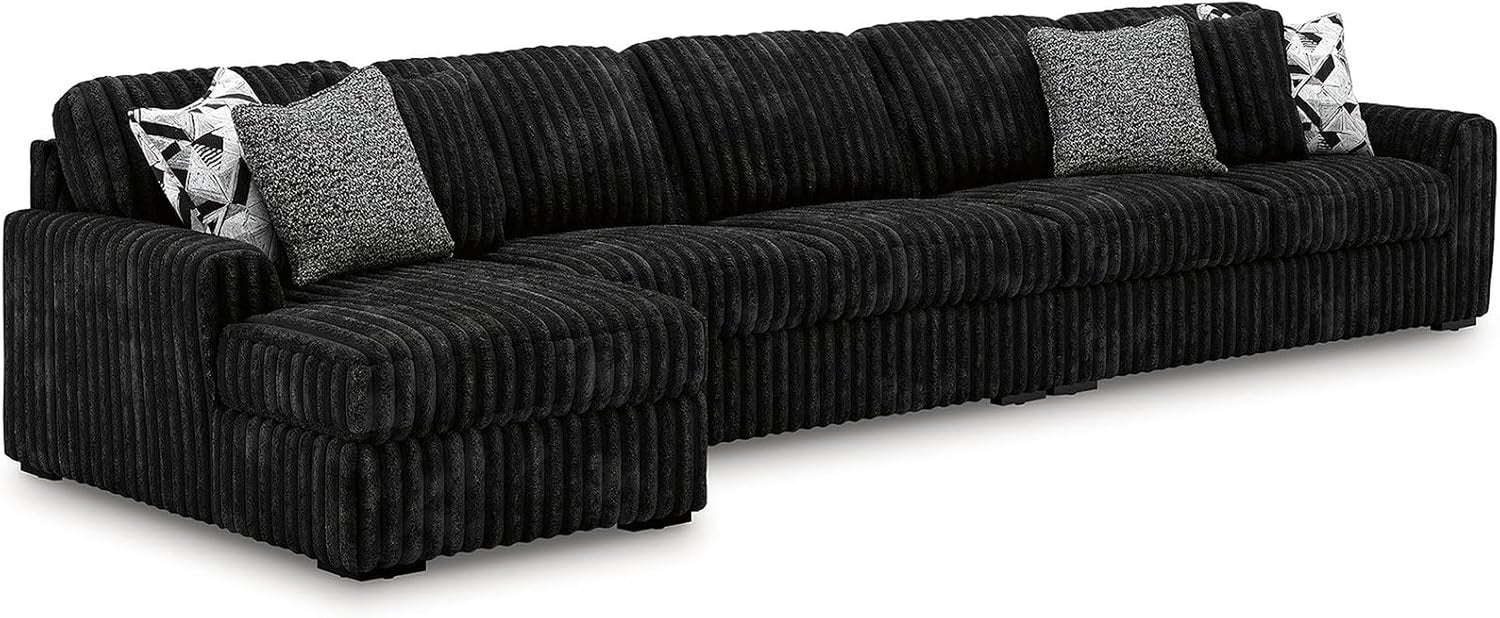 Long black corduroy sectional sofa with a left chaise and three decorative pillows.