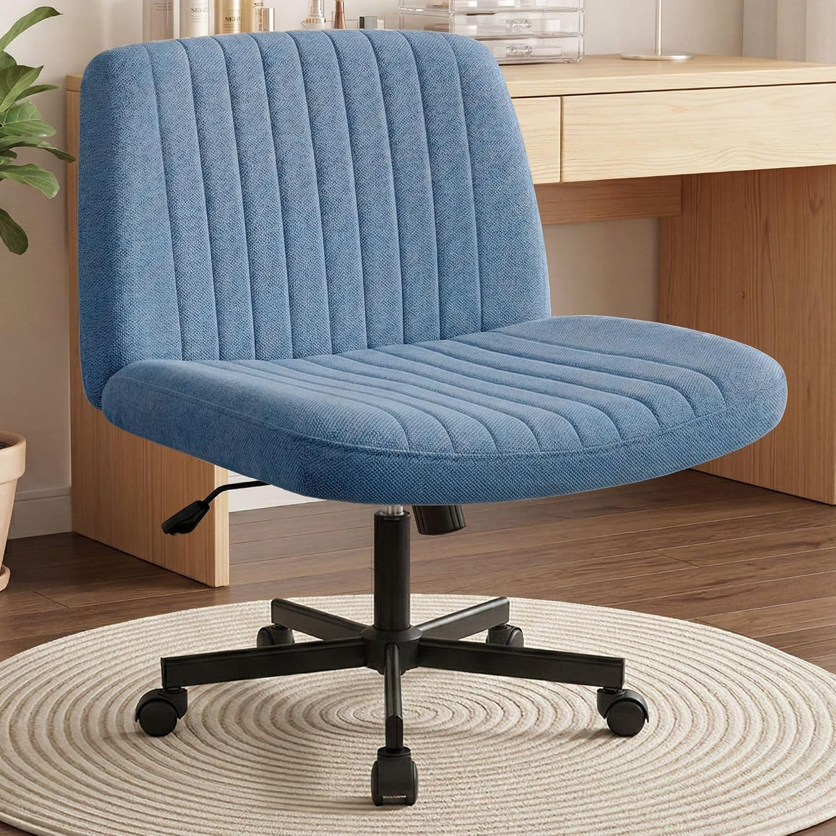 Blue upholstered swivel desk chair with channel-tufted back and black five-star base on a round rug.