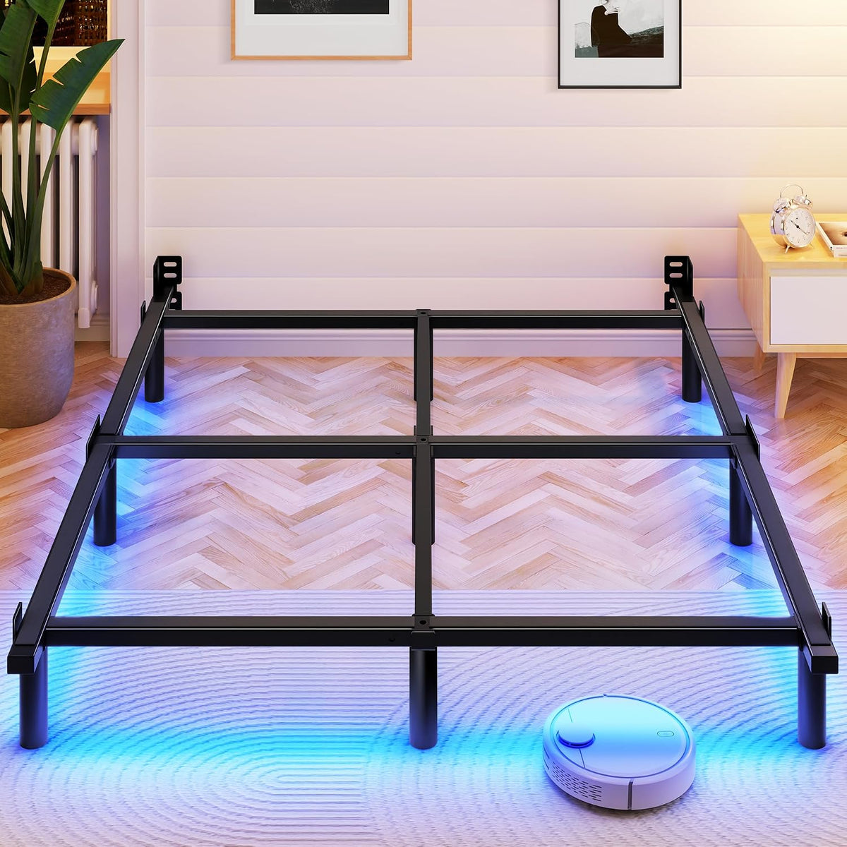 Empty black metal bed frame assembled on herringbone floor with blue underlighting and a robot vacuum near the foot