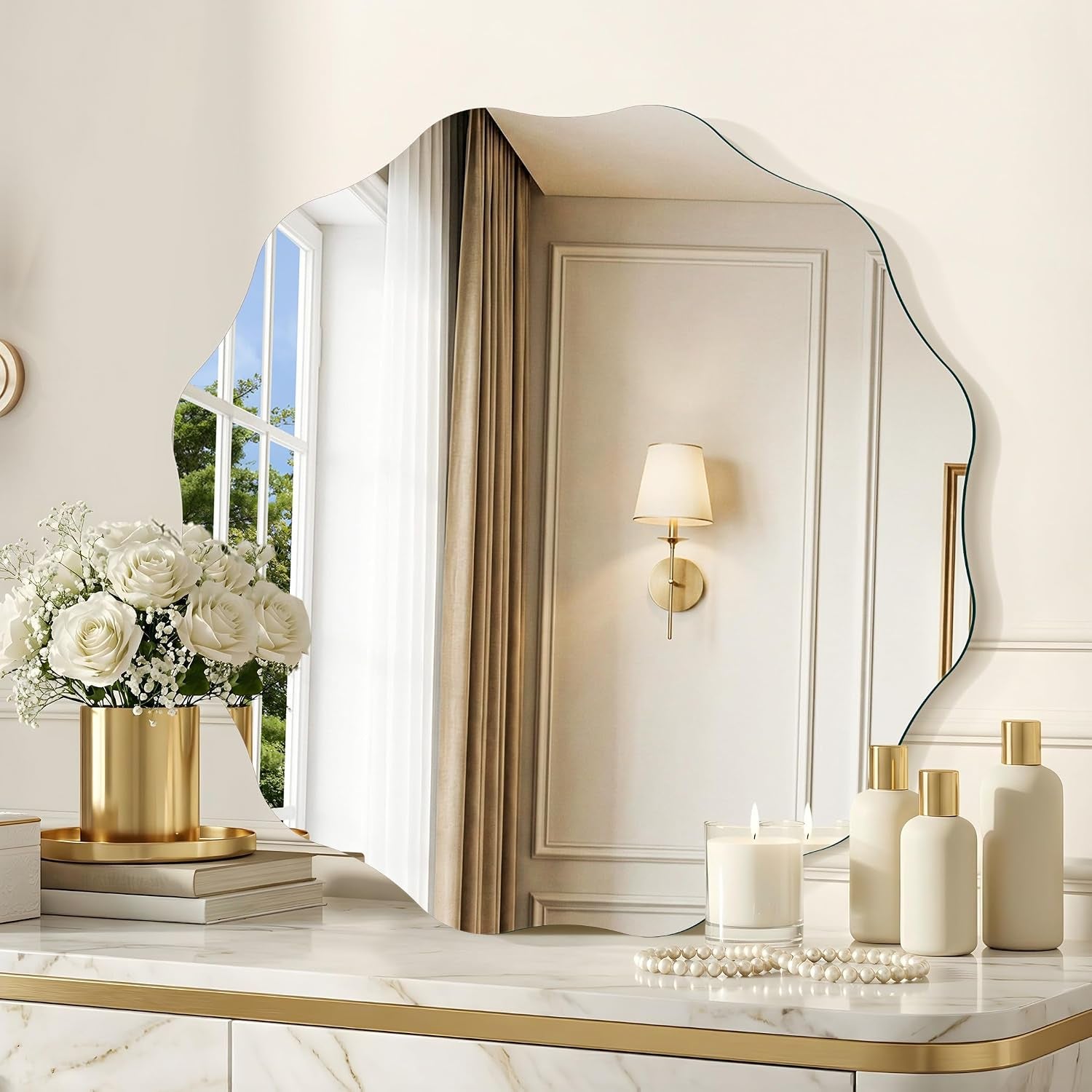 Detail shot of scalloped mirror over a tabletop styled with a coiled string of pearls and three matte cream bottles with