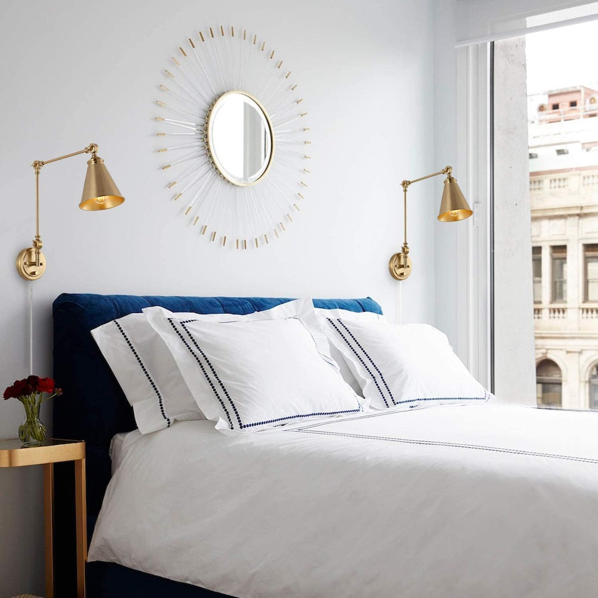 Two brass adjustable swing-arm sconces installed over a bed providing directed task lighting in a bedroom.