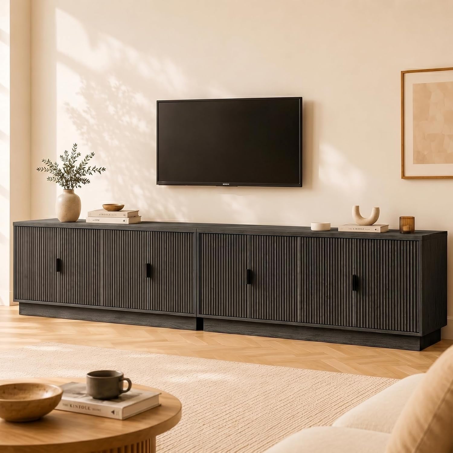 Long low charcoal media console with ribbed front doors beneath a wall-mounted TV in a living room.