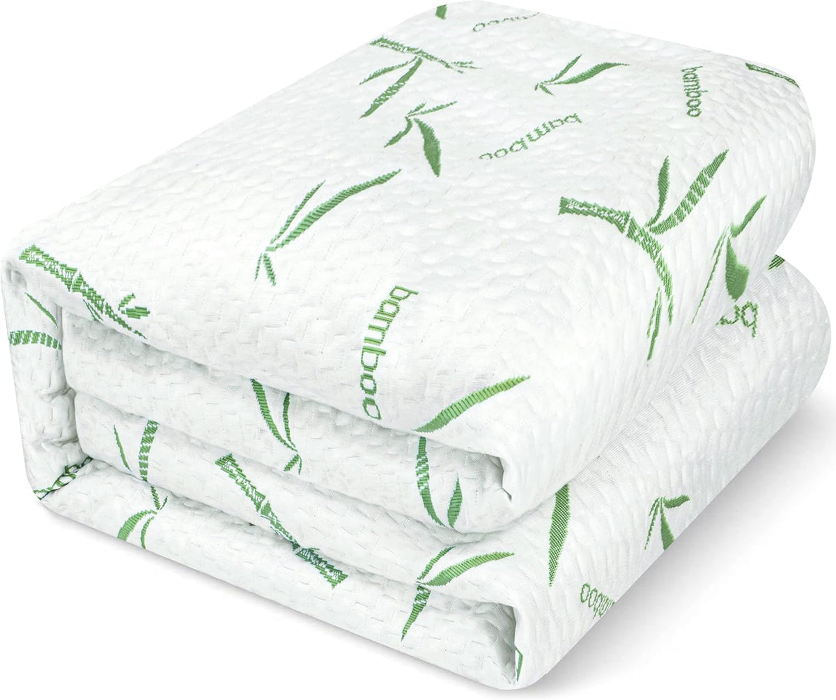 Close-up of the mattress protector folded into a neat stack showing green bamboo print on textured white fabric.