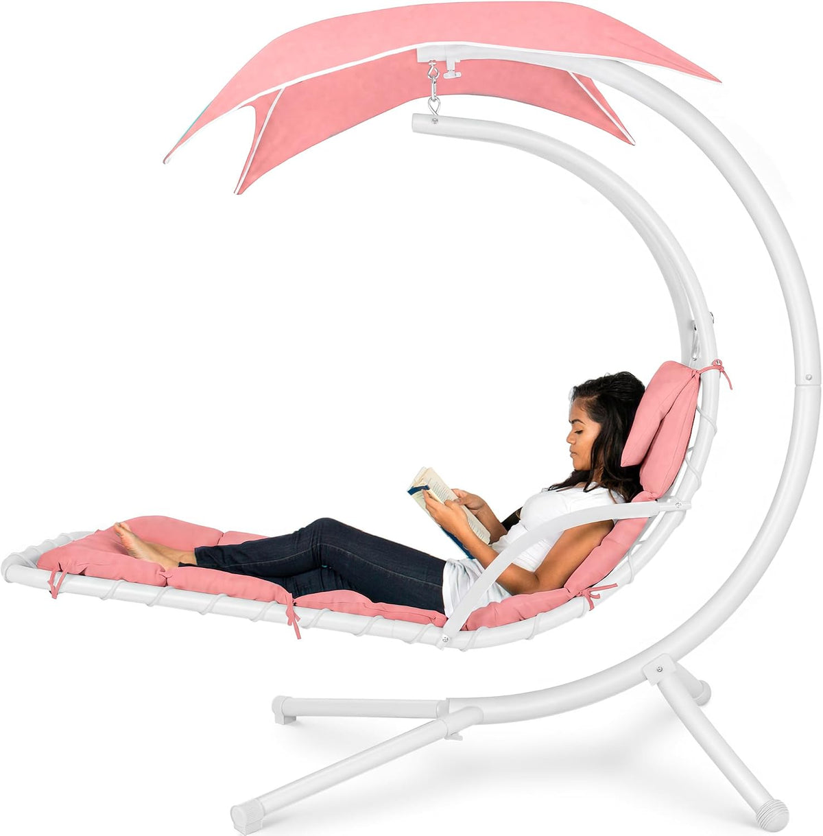 Curved hanging chaise swing in white frame with pink cushions and canopy, woman reclining reading