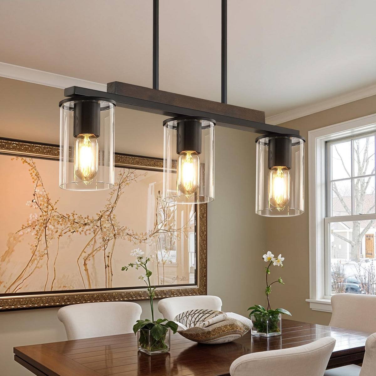 Close-up of three clear glass cylinder shades showing glowing filament bulbs and black metal fittings.