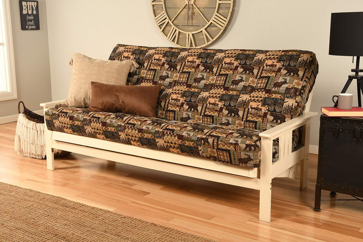 Full view of a futon with a white-painted hardwood frame and a nature-patterned mattress cover, pillows and wall clock.