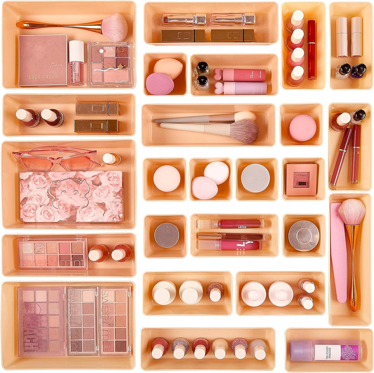 Assortment of peach-colored trays laid out with makeup palettes, brushes and lipsticks