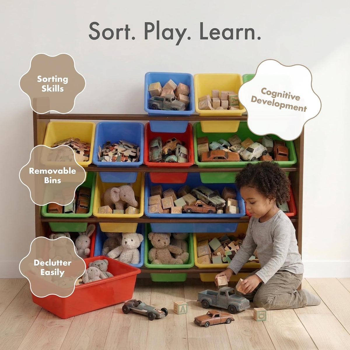 Child kneeling beside the toy organizer pulling blocks from a bin while toys and an empty red bin sit on the floor