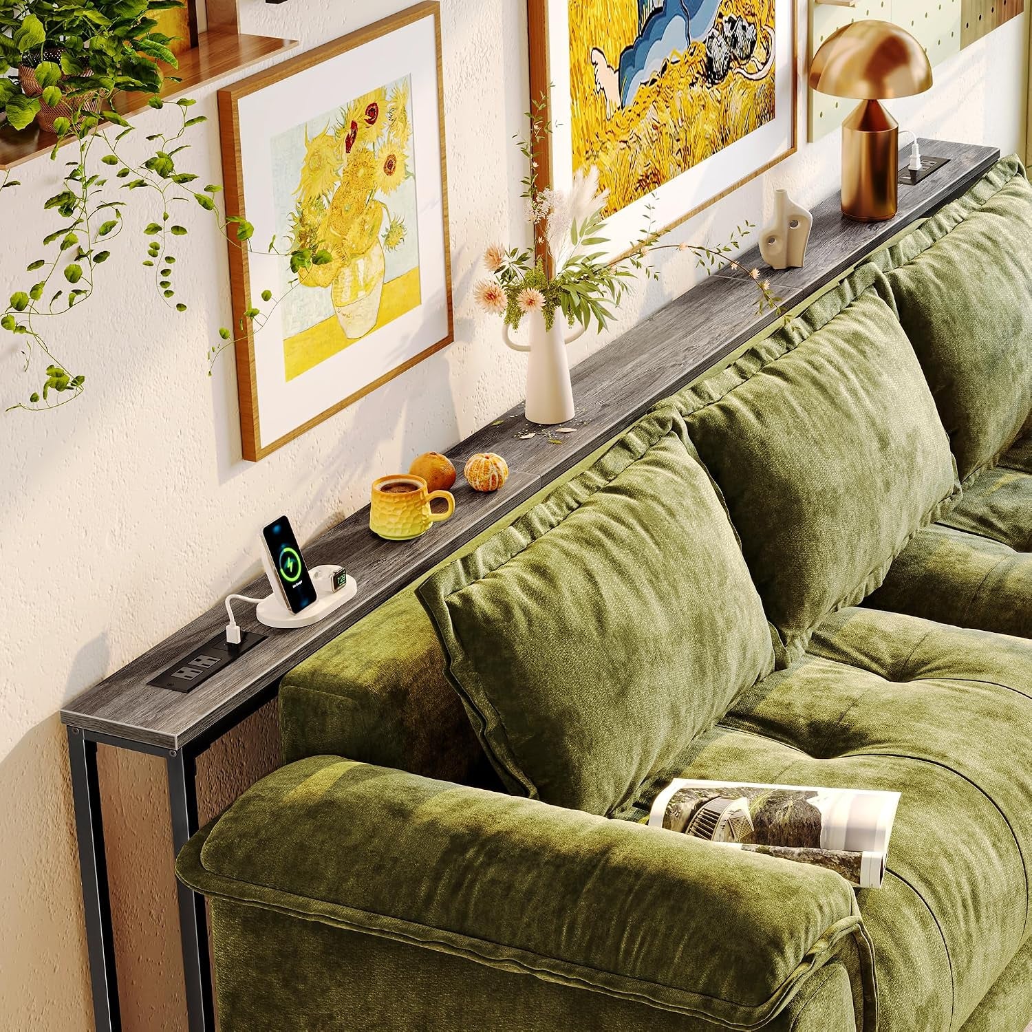 Long narrow console table behind a green sofa with a wood-grain top, power outlet module and decorative items