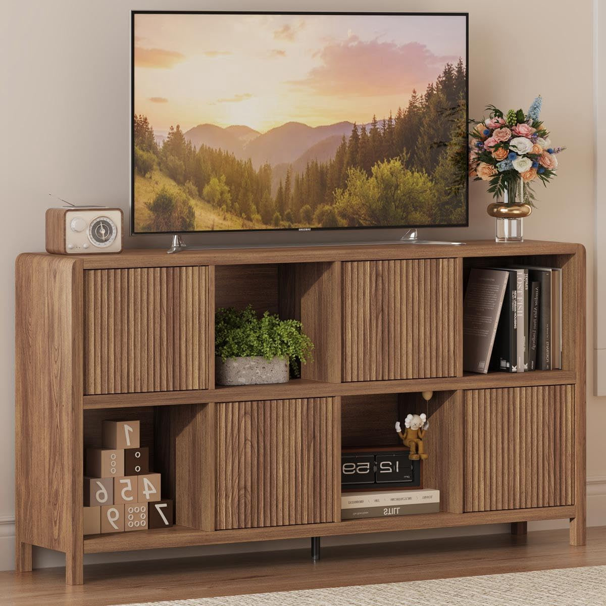 Walnut horizontal bookcase used as TV stand, ribbed doors and open shelves holding books and decor.