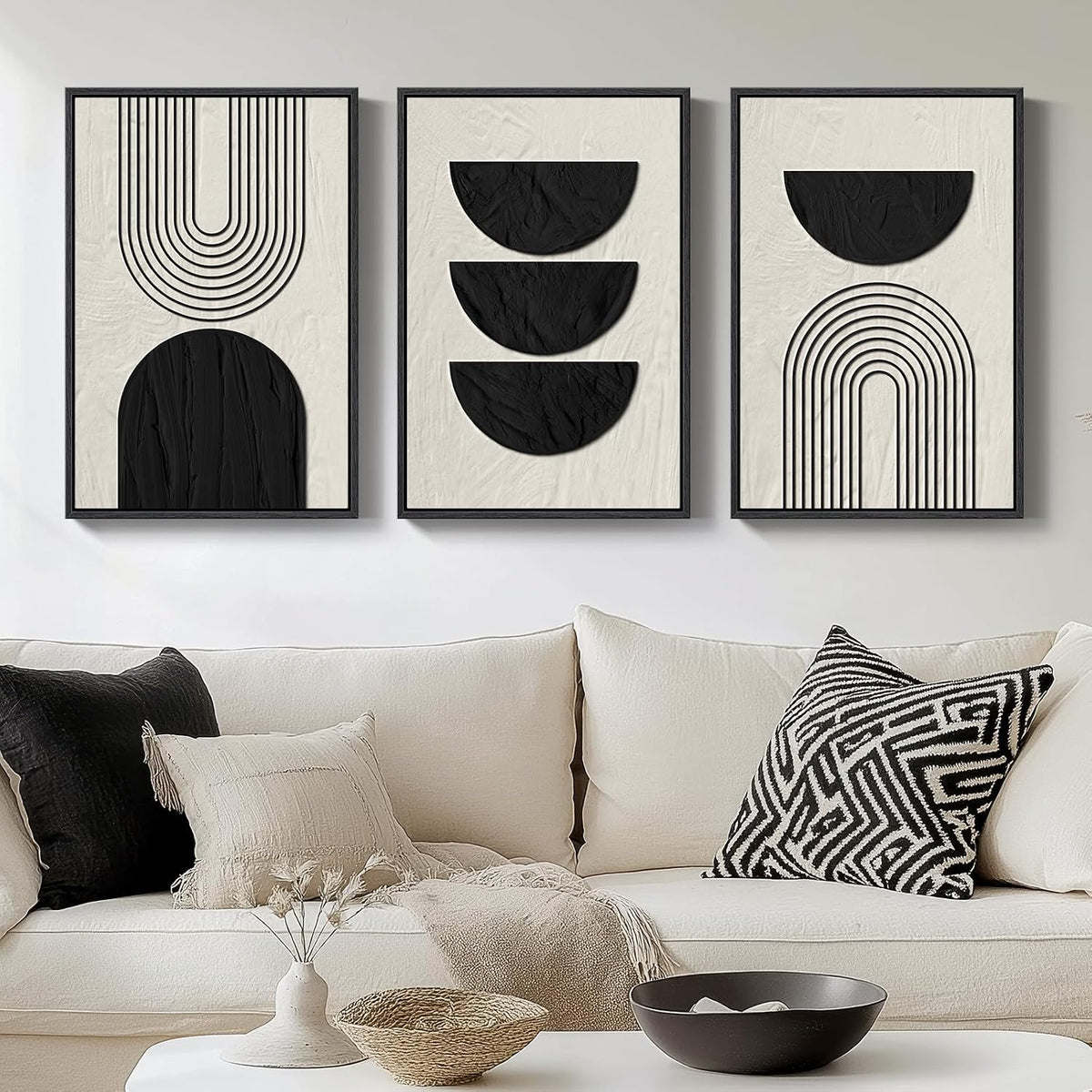 Three framed prints showing black semicircles and arch linework on a cream textured background above a light sofa.