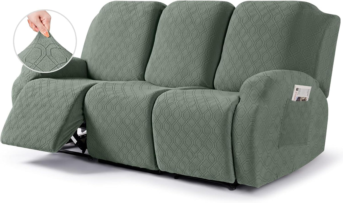 Three-seat reclining sofa covered in sage green textured slipcover with one footrest extended and arm pocket.