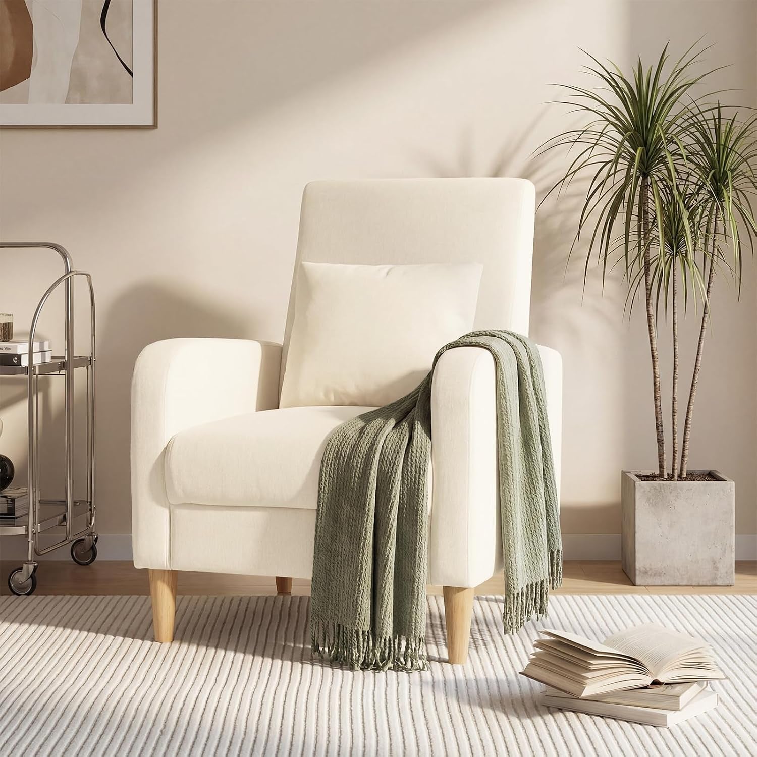 Single beige chair with wooden legs, a pillow and a green throw draped over the arm.
