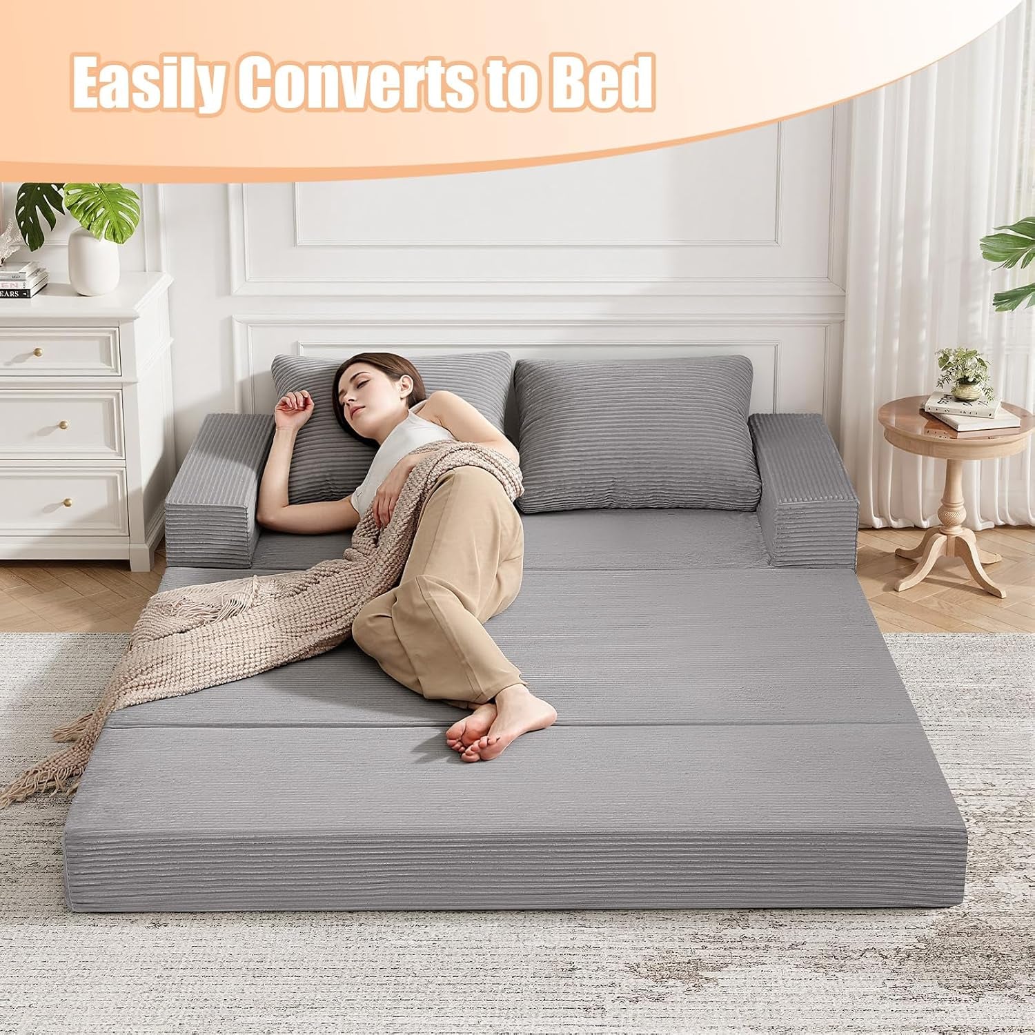 Grey futon mattress fully extended on floor with woman reclining, showing flat sleeper surface