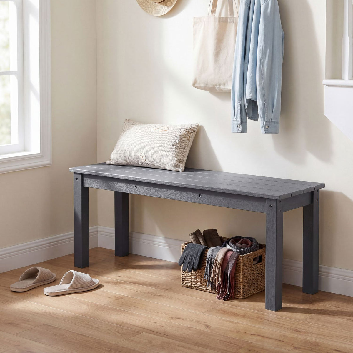 Dark gray slatted bench beneath wall hooks, with a cushion on top and a woven basket underneath.