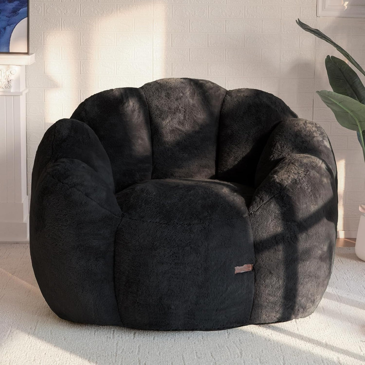 Plush floral-shaped bean bag chair in dark charcoal positioned in a sunlit room on a neutral rug.