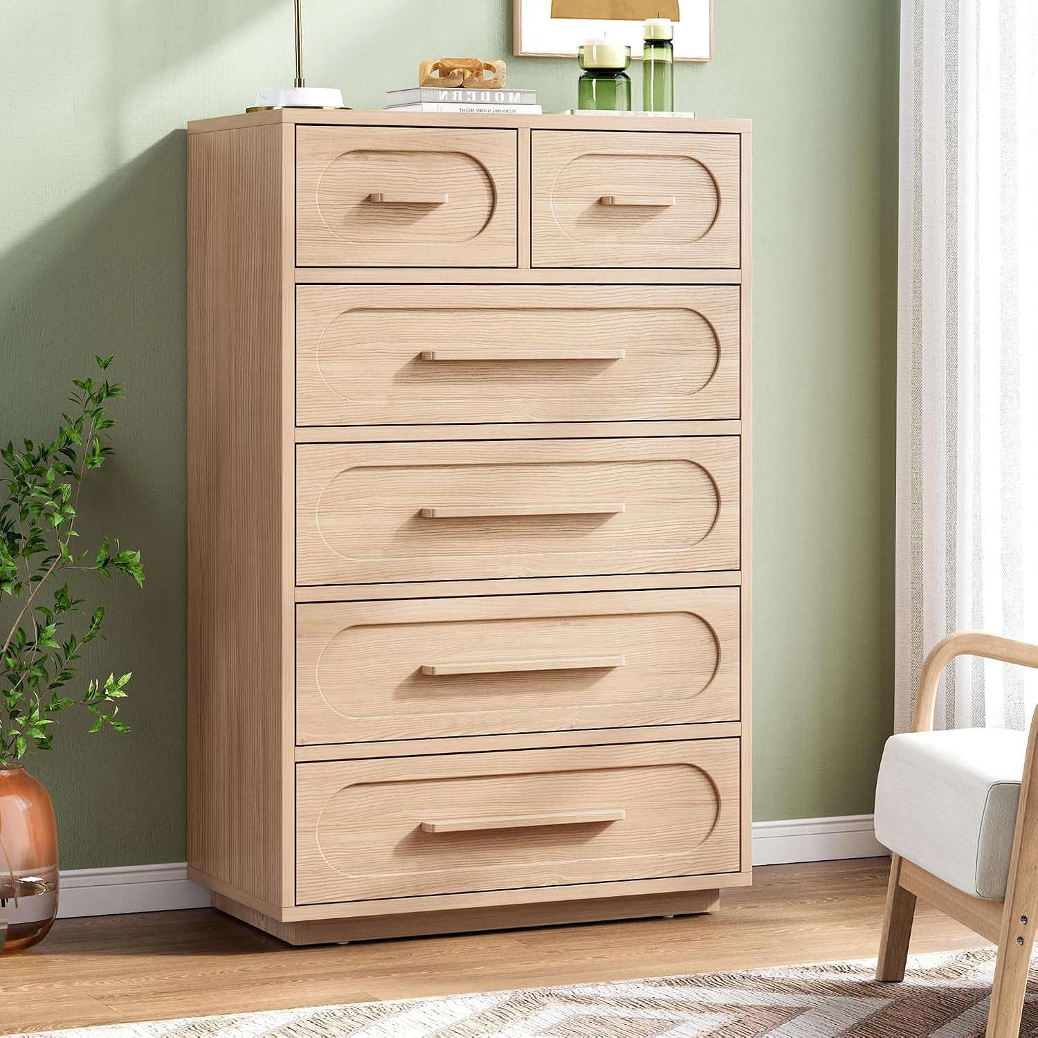 Tall light oak 6-drawer dresser with oval recessed drawer fronts standing against a green wall