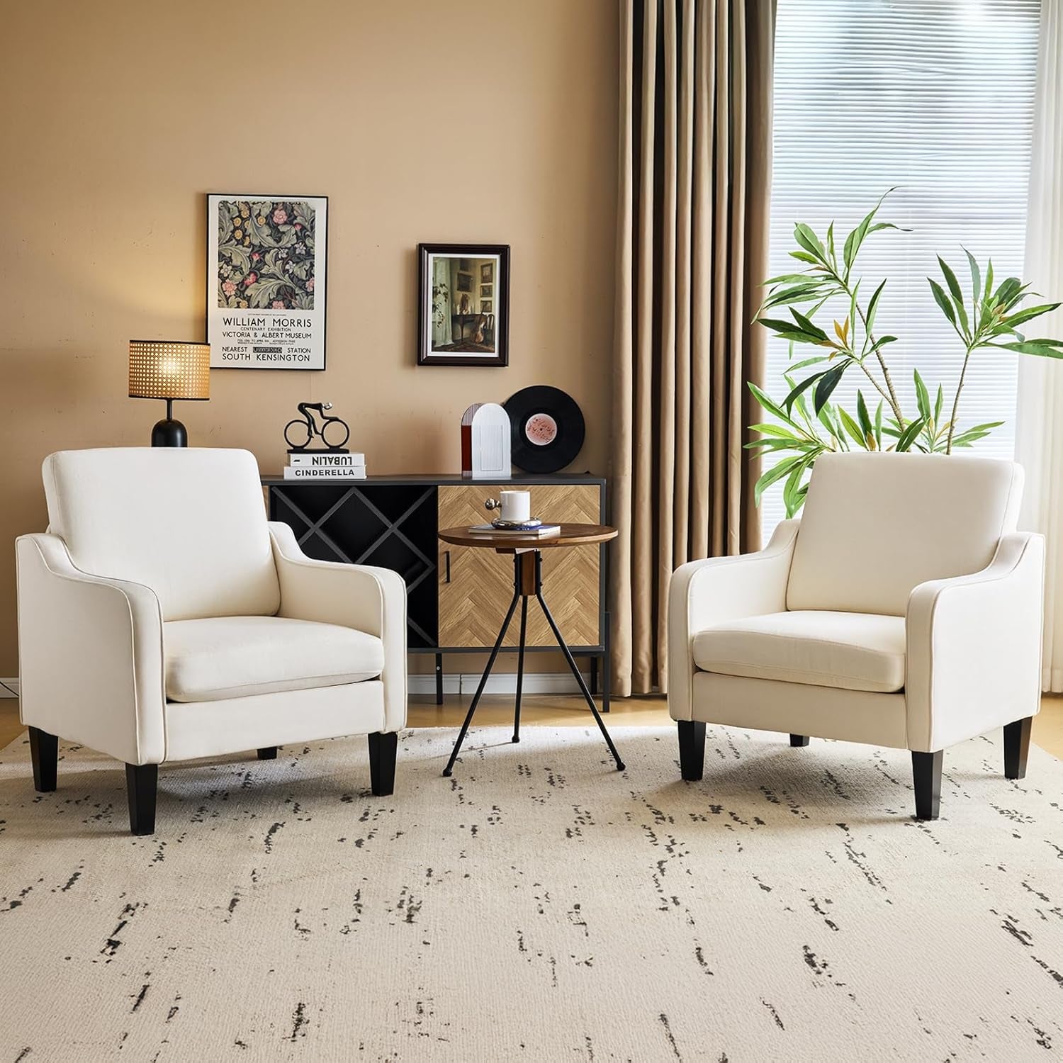 Two cream upholstered accent chairs flanking a small round table in a warmly styled living room.
