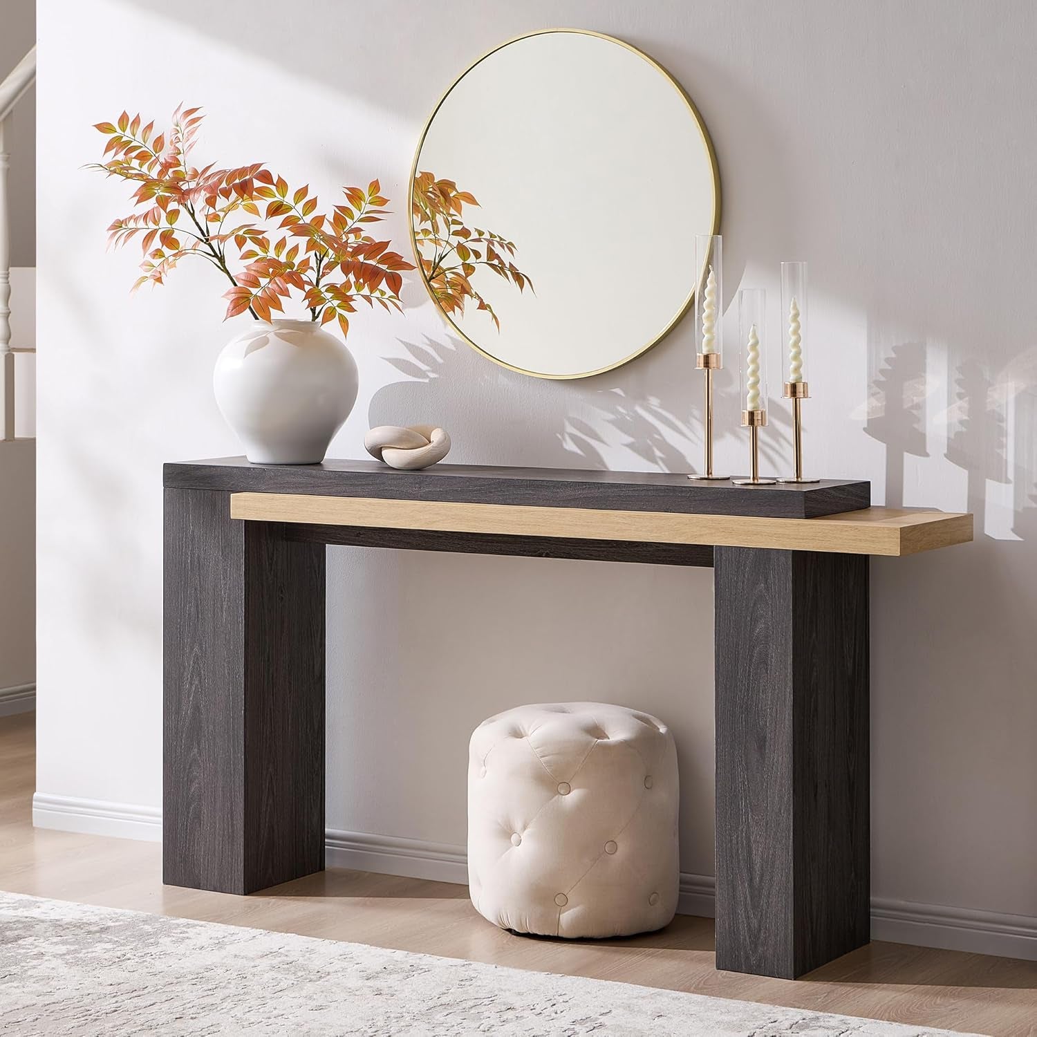 Two-tone console with dark gray base and lighter wood top, styled with candles and a round mirror above.