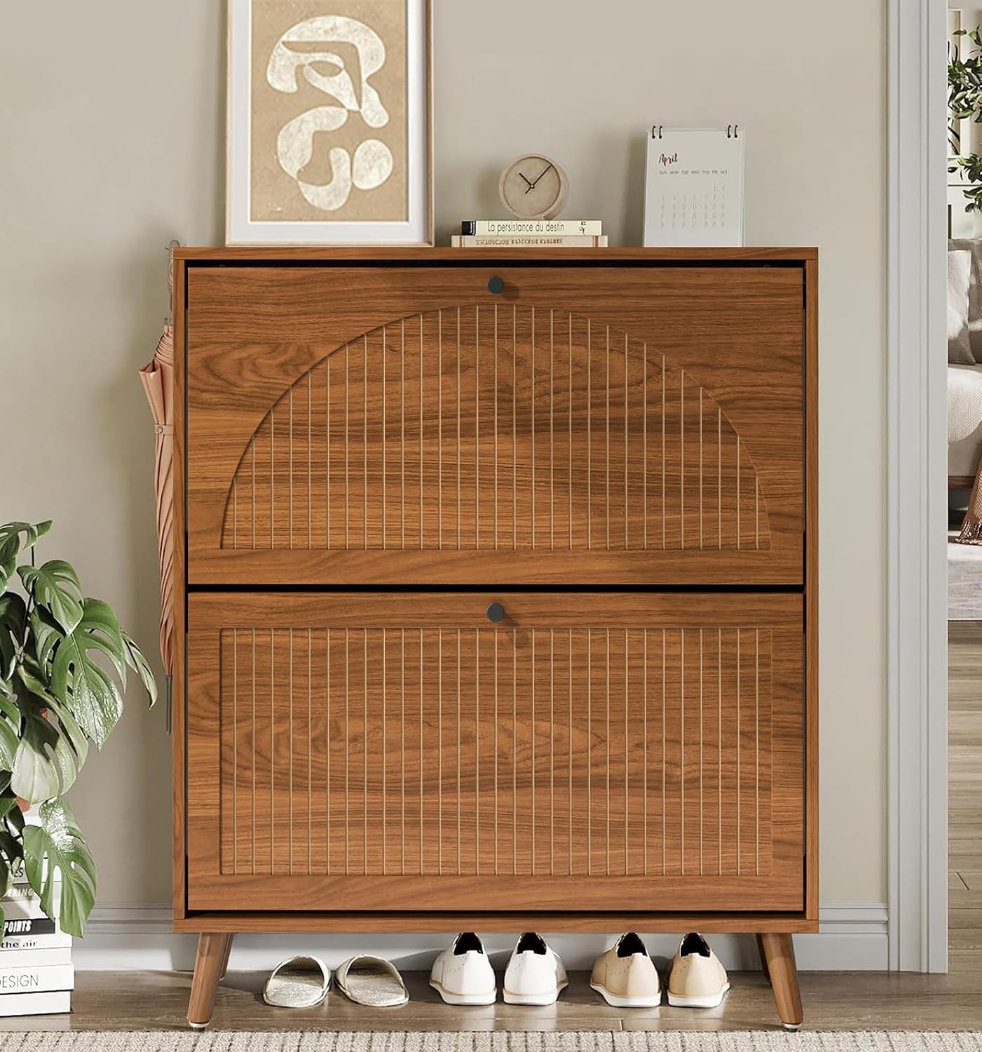 Front view of walnut shoe cabinet in an entryway showing shoes stored beneath and decorative items on the top surface
