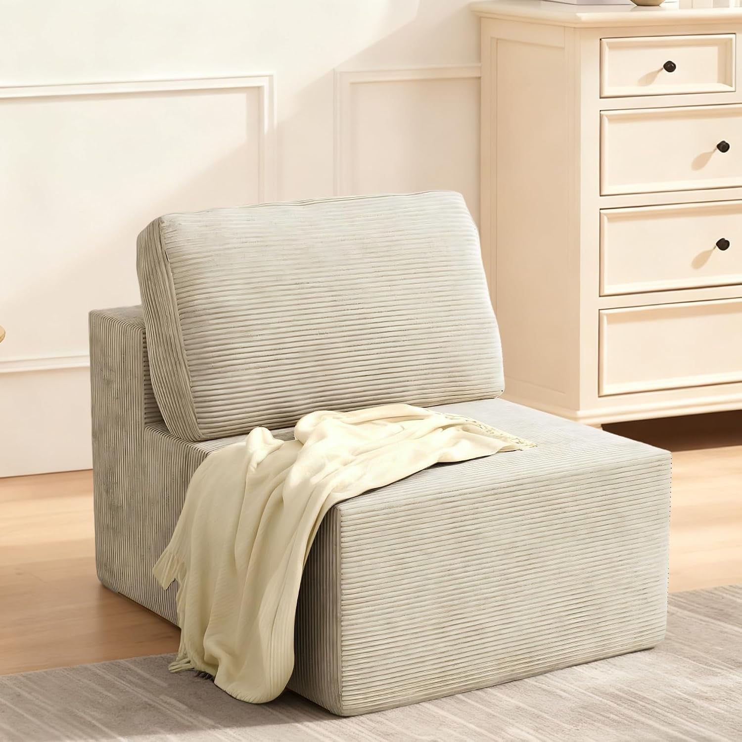 Light beige corduroy modular chair with back cushion and a cream throw draped over seat.